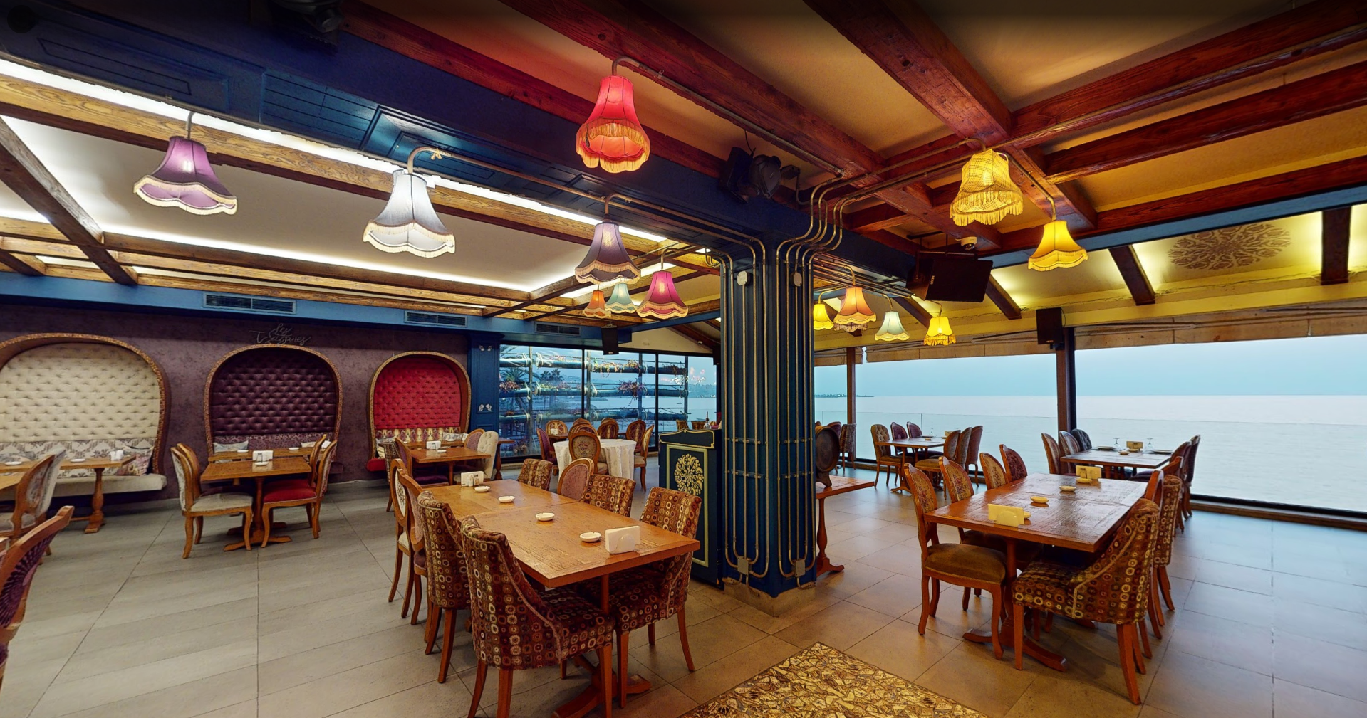 Interior of Les Tziganes restaurant with hanging lamps and sea view
